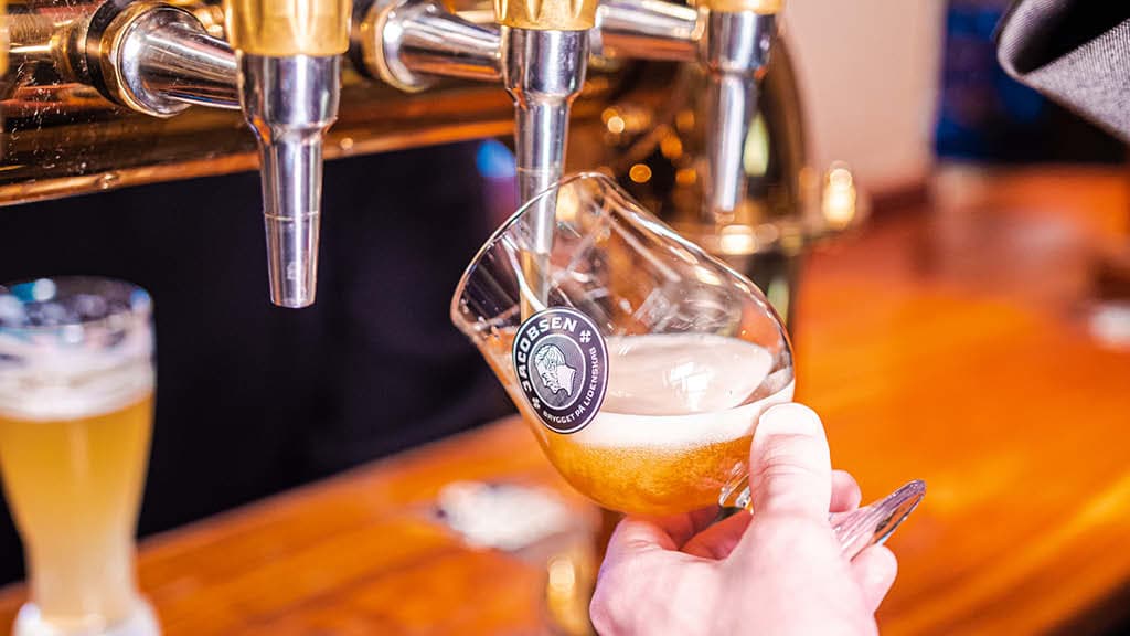 Hand pouring draft beer into a glass