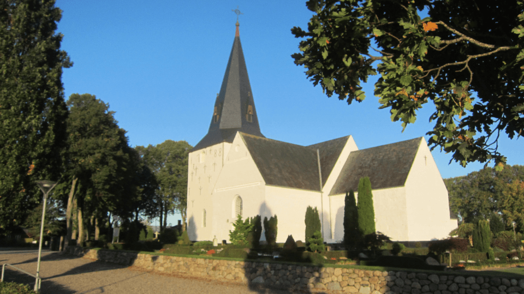 Whitewashed church with a steeple and a grey roof